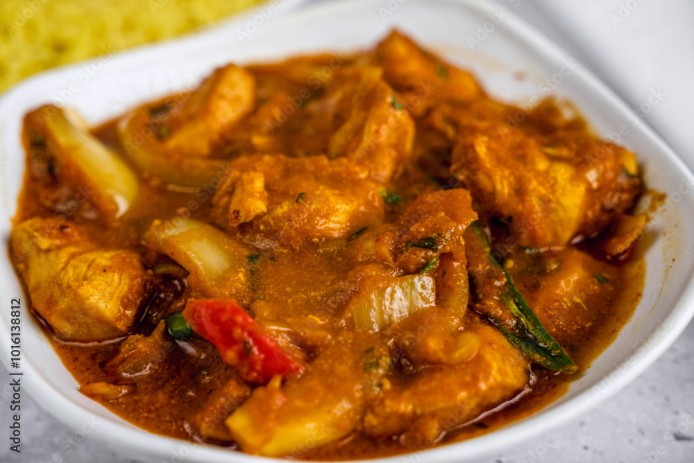 Delicious plate of chicken curry was served in a white bowl, showcasing tender chicken pieces in a rich, spicy sauce with visible vegetables and herbs. Delicious plate of chicken curry was served in a white bowl, showcasing tender chicken pieces in a rich, spicy sauce with visible vegetables and herbs.