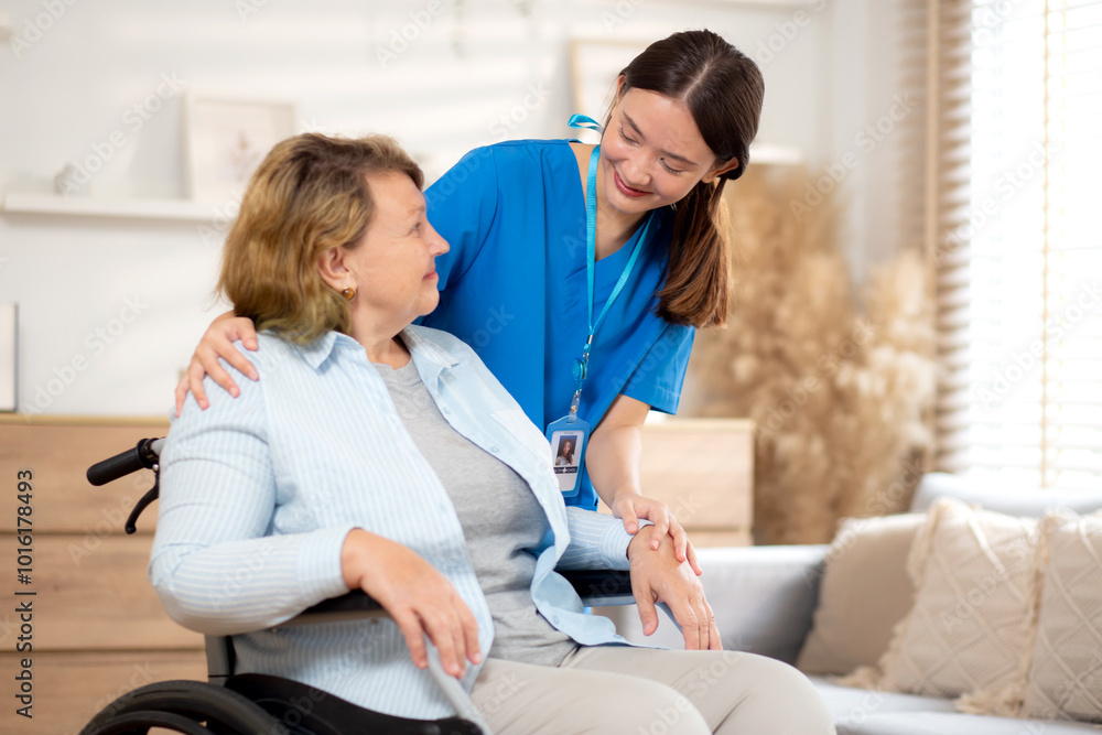 Fototapeta premium Caregiver young woman care elderly sitting on wheelchair and encourage in living room at home, senior therapy with doctor, doctor encourage with patient and support, insurance and medical.