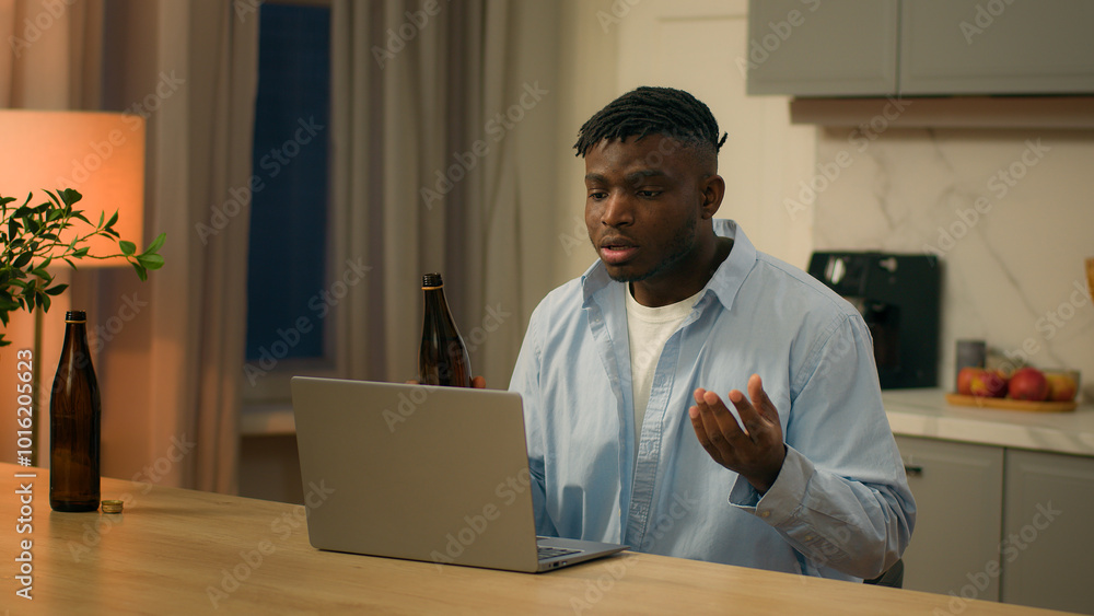 Alcohol addict drunk African American man guy sad stressed angry dissatisfied failure male at evening home drinking beer stress problem with laptop computer video call conference talk online game lost Alcohol addict drunk African American man guy sad stressed angry dissatisfied failure male at evening home drinking beer stress problem with laptop computer video call conference talk online game lost