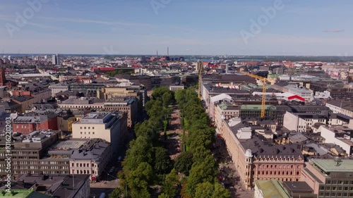 Aerial views highlight Helsinki city center, showcasing the beautiful esplanadi park and impressive architecture. The scene captures a lively urban landscape beneath a clear blue sky photo