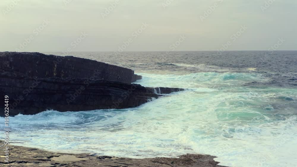 Pan shot of ocean waves crashing rocks on Loop Head Peninsula and Bridges of Ross area at evening, Ireland Pan shot of ocean waves crashing rocks on Loop Head Peninsula and Bridges of Ross area at evening, Ireland