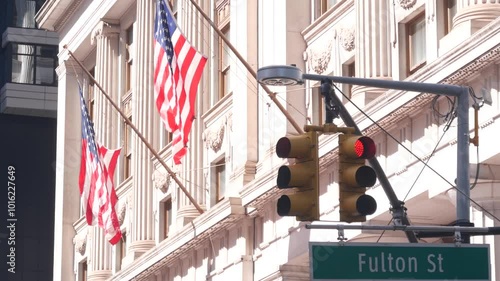 New York City crossroad, Fulton street intersection road sign. Manhattan downtown financial district architecture, NYC, United States. Yellow traffic light, american flag and roadsign near Broadway.