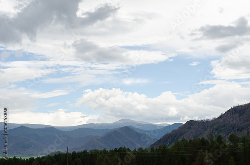 Mountain slopes with clouds on the sky covered with valley on top and mountains in Altay Russia early in the evening sunset. Hight quality horizontal photo