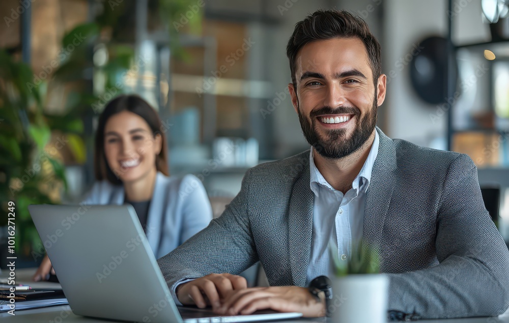 Two business professionals smiling in a modern office setting with laptops and warm lighting Two business professionals smiling in a modern office setting with laptops and warm lighting