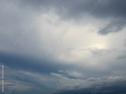 An intense sky with swirling clouds in shades of gray and blue, as strong winds push the clouds across the horizon, creating dramatic shapes 