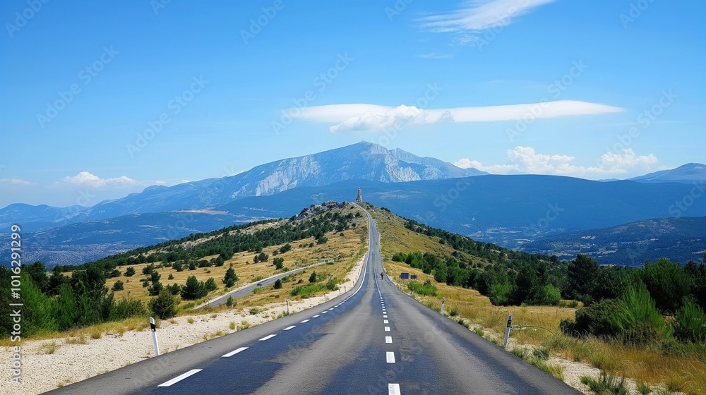 Winding road leads to majestic mountain range in France. Gray road contrasts with rich plants of trees, shrubs. Panoramic view of road, surroundings from vantage point. Blue sky with scattered clouds Winding road leads to majestic mountain range in France. Gray road contrasts with rich plants of trees, shrubs. Panoramic view of road, surroundings from vantage point. Blue sky with scattered clouds