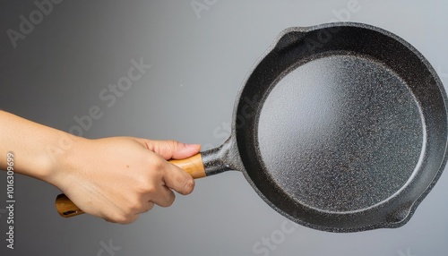 Hand holding a cast iron skillet on a gray background. photo