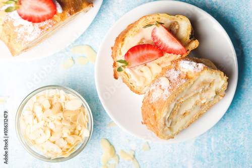Sliced rolls with custard. The dessert is decorated with fresh strawberries.
