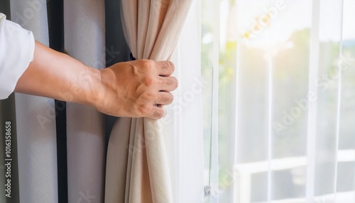 Person pulling back curtains to let sunlight in.