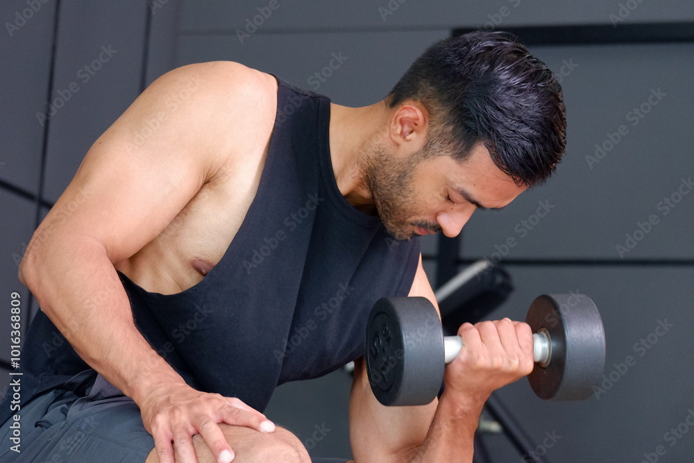 Young man exercising with dumbbells in the gym. Healthy exercise concept. Young man exercising with dumbbells in the gym. Healthy exercise concept.