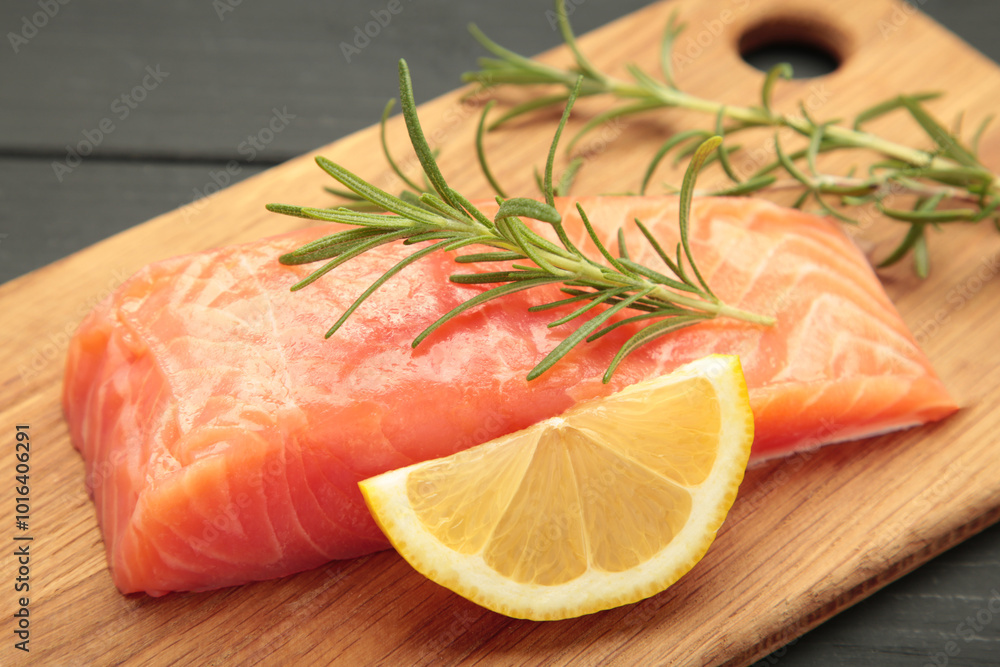 Red fish. Raw salmon fillet with rosemary and lemon on cutting board Red fish. Raw salmon fillet with rosemary and lemon on cutting board