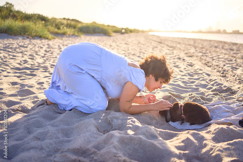 young plus size woman walking and playing with her pet rabbit by the sea in Copenhagen photo