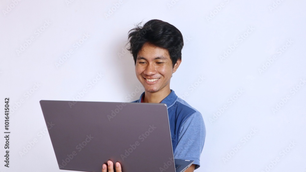 Asian young man smiling gesture holding laptop Asian young man smiling gesture holding laptop