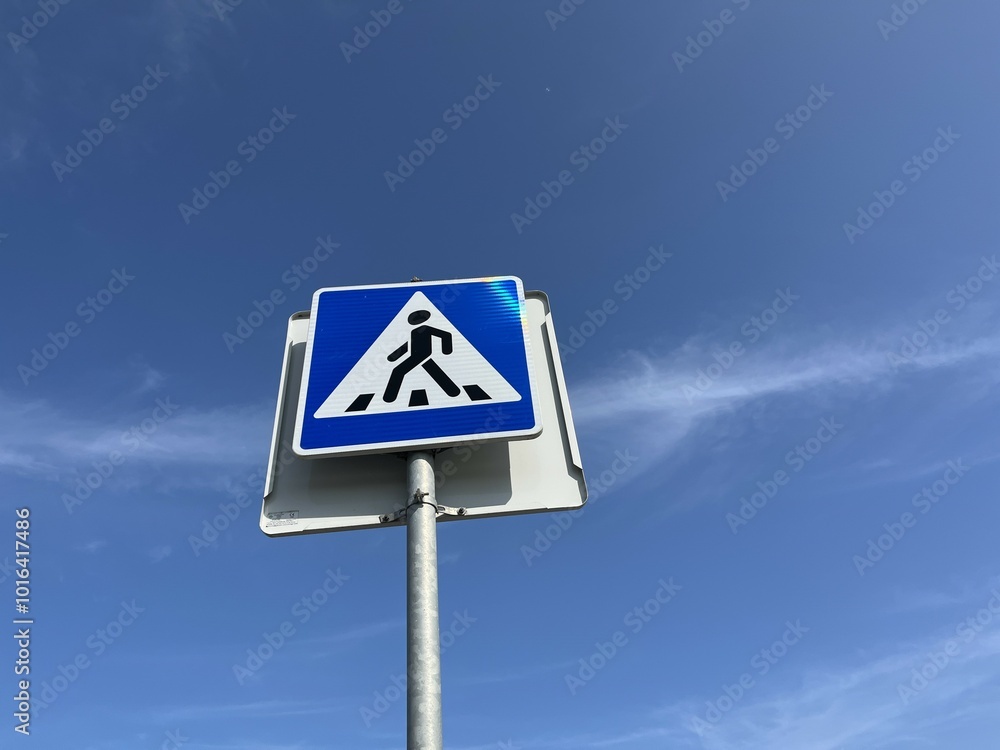 Pedestrian crossing sign with blue sky and clouds in the background Pedestrian crossing sign with blue sky and clouds in the background