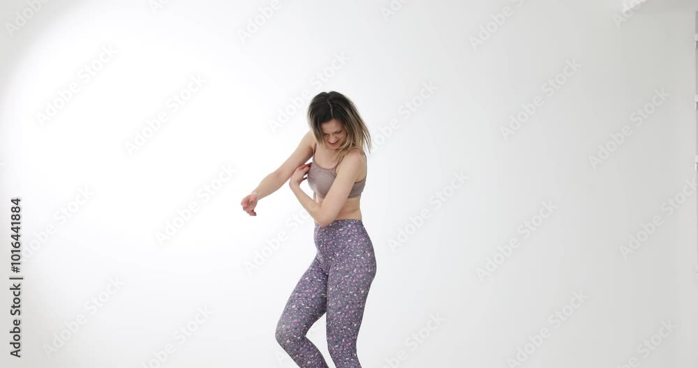 Young woman in bright sportswear prepares body for physical activity. Positive blonde female in sports bra dances to maintain perfect form slow motion Young woman in bright sportswear prepares body for physical activity. Positive blonde female in sports bra dances to maintain perfect form slow motion