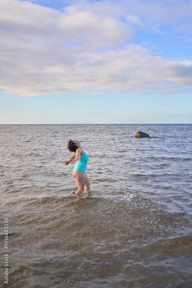 a young plus-size woman is engaged in winter swimming and warming up by the sea a young plus-size woman is engaged in winter swimming and warming up by the sea