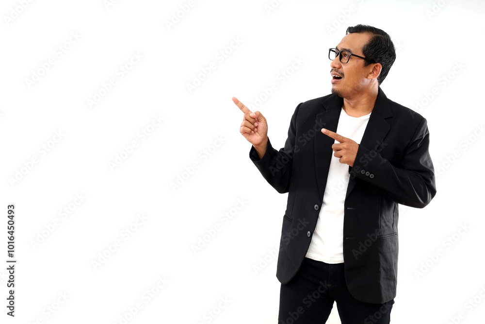 Happy smiling handsome Asian businessman pointing and looking upward on empty space Happy smiling handsome Asian businessman pointing and looking upward on empty space