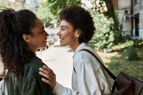 A happy lesbian couple shares laughter while exploring the outdoors on a sunny day.