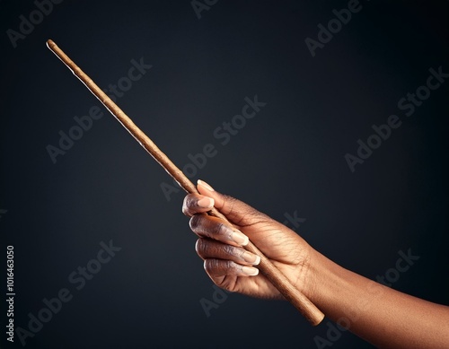 Hand with wooden magic wand, wizard and magician tool. Isolated on dark background.