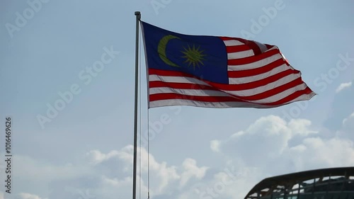 Putra Jaya, Malaysia on May 22, 2023. The Malaysian flag flies at Putra Jaya Square. The sky is bright blue, there are some high mast lights. photo