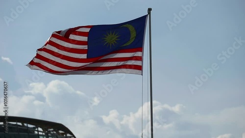 Putra Jaya, Malaysia on May 22, 2023. The Malaysian flag flies at Putra Jaya Square. The sky is bright blue, there are some high mast lights. photo