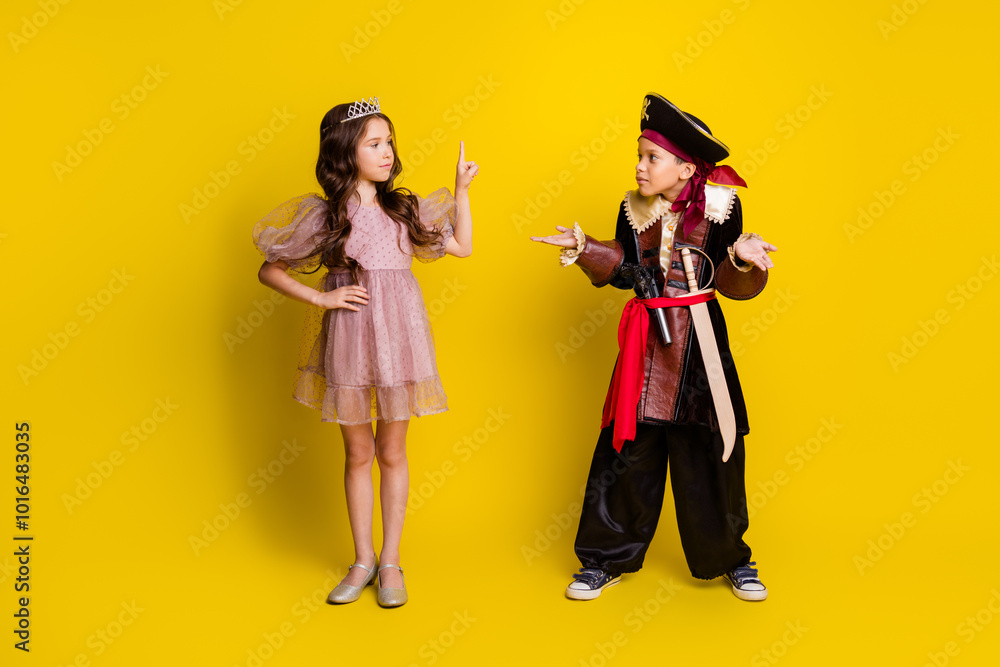 Full body portrait of two small kids point finger shrug shoulders halloween pirate princess costume isolated on yellow color background Full body portrait of two small kids point finger shrug shoulders halloween pirate princess costume isolated on yellow color background