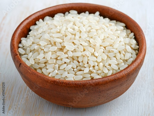 White rice in a ceramic bowl on a light wooden surface.