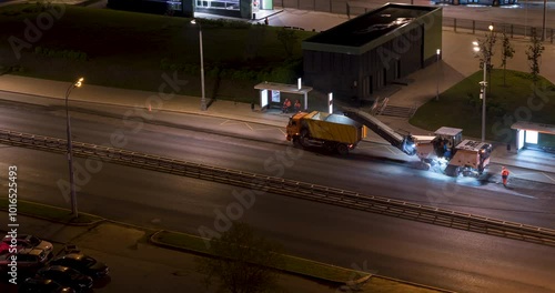 Time lapse of working cold milling machine at the night city highway with hard traffic. Aerial view