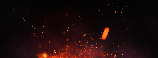 Fire embers particles over black panorama background. Fire burn sparks background. Abstract dark glitter fire particles lights.