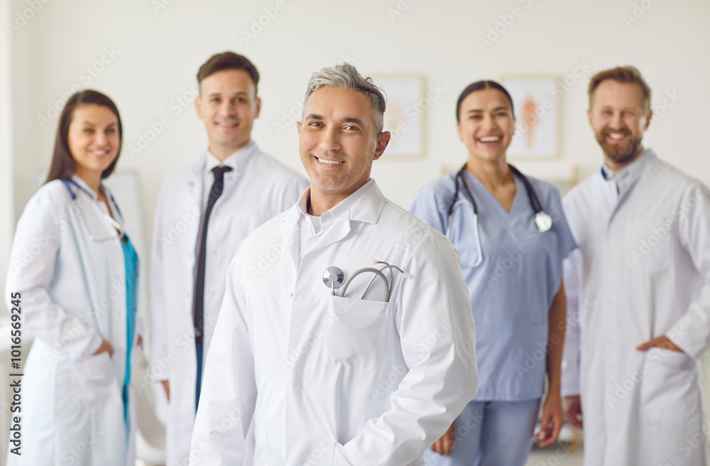 Portrait of a happy successful confident team of doctors in white uniform looking cheerful at camera and smiling standing in hospital or clinic. Medical staff, medicine and health care concept. Portrait of a happy successful confident team of doctors in white uniform looking cheerful at camera and smiling standing in hospital or clinic. Medical staff, medicine and health care concept.