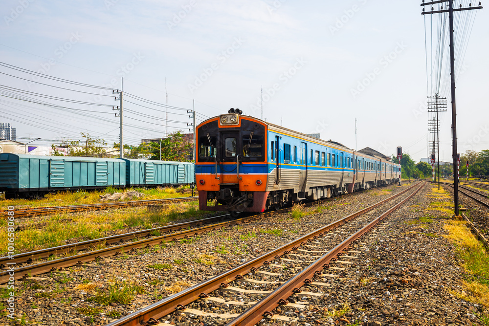 Obraz premium Diesel rail is a fast intercity train in Thailand with many tracks and traffic lights and freight cars in the background.