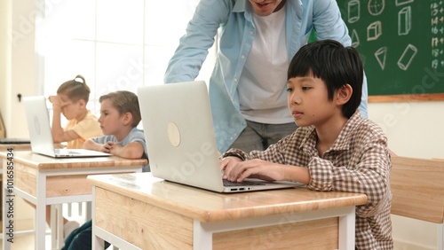 Caucasian teacher helping asian student coding engineering prompt while diverse student using software generated AI. Smart happy attractive children sitting and programing system. Education. Pedagogy.