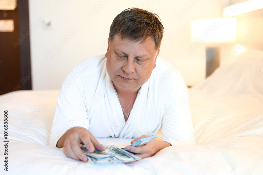 Man white robe lying on bed counting cash dollars concept of successful life. Man white robe lying on bed counting cash dollars concept of successful life.