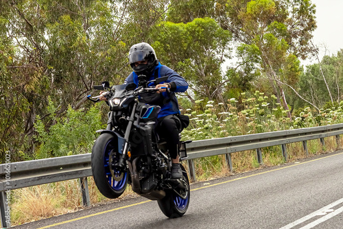 Photos A motorcycle racer performs a difficult and dangerous stunt on his motorcycle