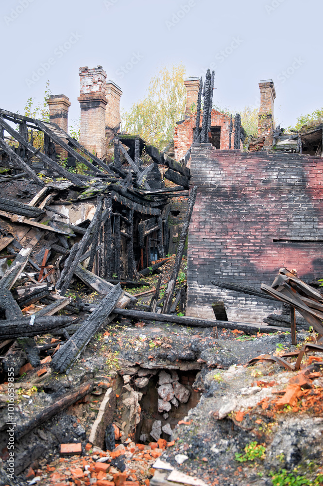 Burnt ruins of a collapsed house with charred remains surrounded by nature Burnt ruins of a collapsed house with charred remains surrounded by nature