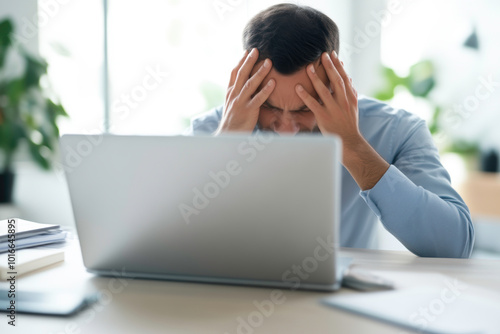 A man is sitting at a desk with a laptop and a keyboard