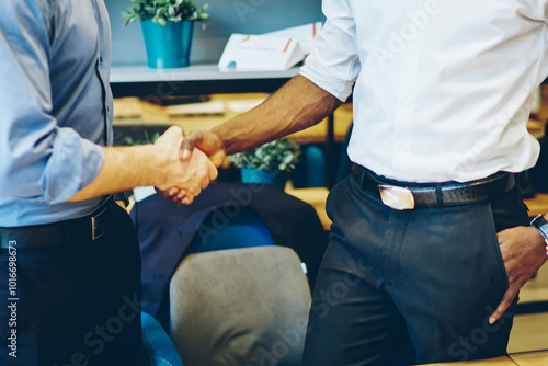 Cropped view of multicultural businessmen dressed in formal wear making deal and handshaking standing in office interior.Diverse entrepreneurs greeting each other during important corporate meeting