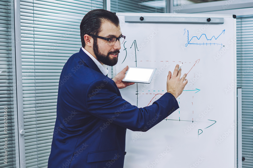 Intelligent male businessman spending time for speaking main information about time of growth company using graphic on flip chart and information from smartphone with blank screen area for your text Intelligent male businessman spending time for speaking main information about time of growth company using graphic on flip chart and information from smartphone with blank screen area for your text