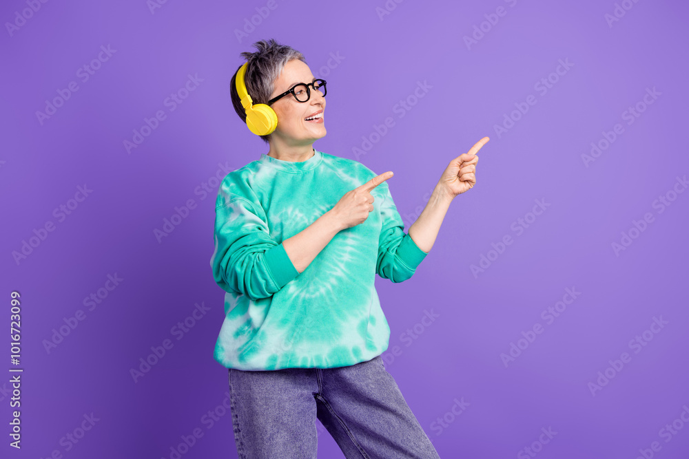 Photo portrait of pretty retired female earphones point look empty space wear trendy green outfit isolated on violet color background Photo portrait of pretty retired female earphones point look empty space wear trendy green outfit isolated on violet color background