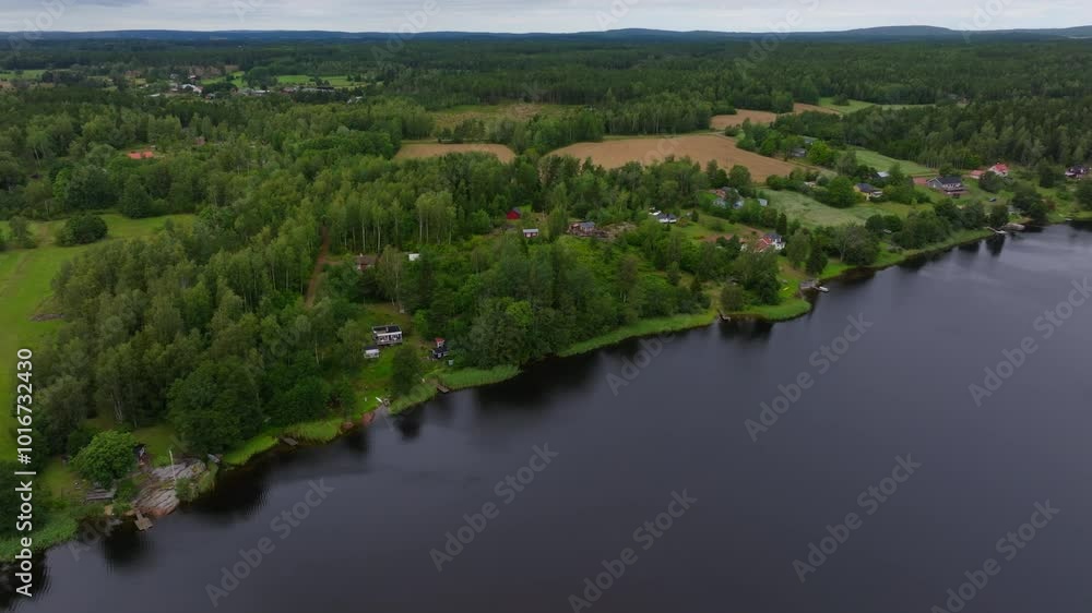 Lush green trees and fields meet the deep blue water of the Baltic Sea in the Aland islands, Finland. Red roofed houses dot the landscape Lush green trees and fields meet the deep blue water of the Baltic Sea in the Aland islands, Finland. Red roofed houses dot the landscape