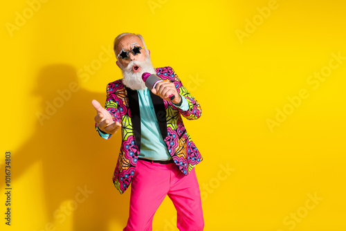 Photo portrait of attractive retired man star sunglass sing karaoke dressed colorful pink fancy clothes isolated on yellow color background photo