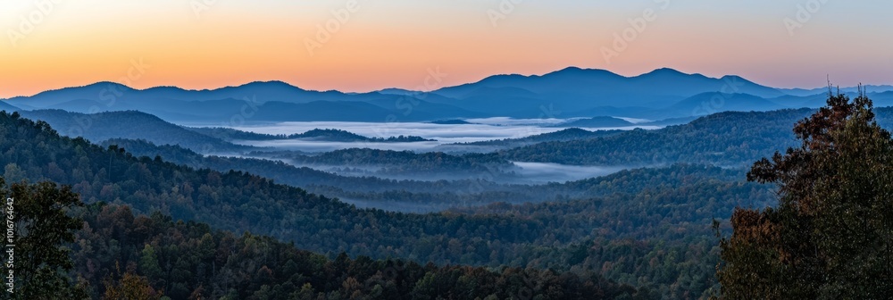 Naklejka premium At sunset, a mountain range is framed by low-lying clouds, with trees lining the foreground