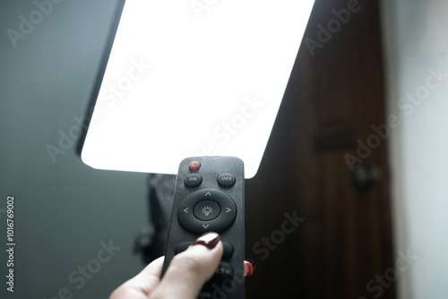 Hand Using Remote to Control Bright LED Light Panel