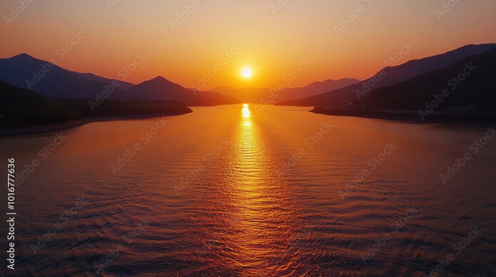 A fiery sunset casts an orange glow over a calm lake, with mountains in the background. A fiery sunset casts an orange glow over a calm lake, with mountains in the background.