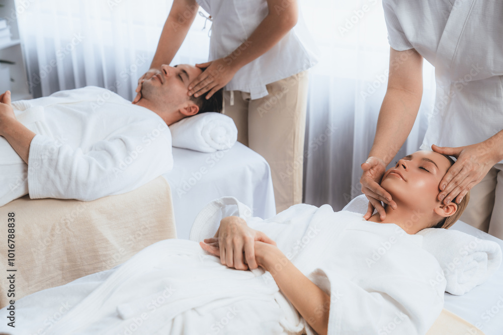 Fototapeta premium Caucasian couple enjoying relaxing anti-stress head massage and pampering facial beauty skin recreation leisure in dayspa modern light ambient at luxury resort or hotel spa salon. Quiescent