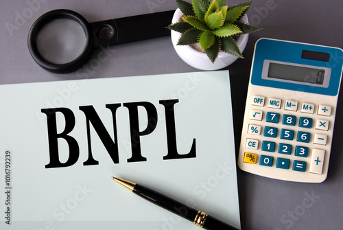 Fotografija BNPL - acronym on paper with a pen on the background of a calculator, magnifying