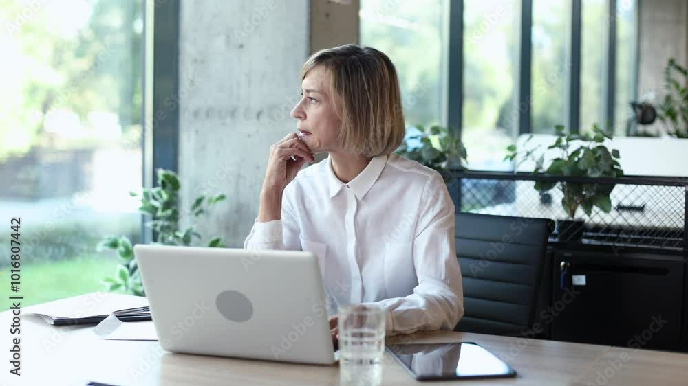 Unhappy frustrated middle aged female holding head by hands sitting with computer behind desk at office. Unhappy frustrated middle aged female holding head by hands sitting with computer behind desk at office.