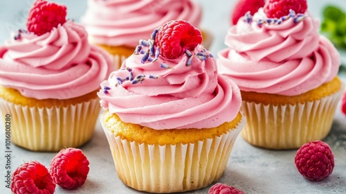 Raspberry cupcakes with pink blossoms and fresh raspberries on top.