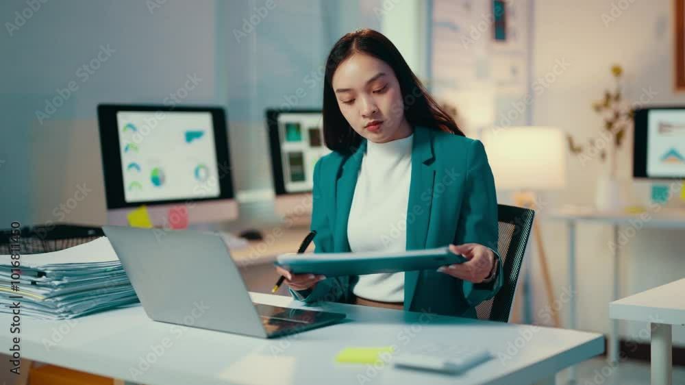 Asian accountant reviews documents and takes notes at her desk, utilizing a tablet and laptop to manage financial tasks and ensure accurate accounting practices Asian accountant reviews documents and takes notes at her desk, utilizing a tablet and laptop to manage financial tasks and ensure accurate accounting practices