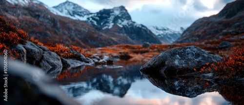  A foreground body of water lies before a mountain range with snow-capped peaks in the background